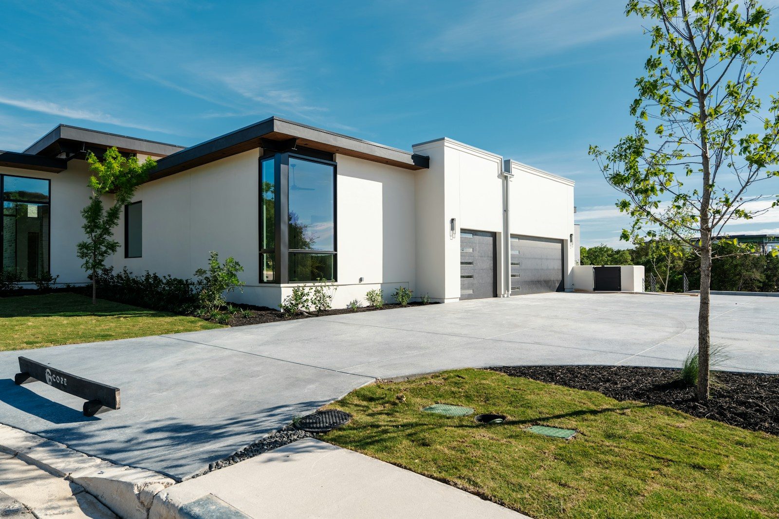 Modern white house with large windows and a concrete driveway
